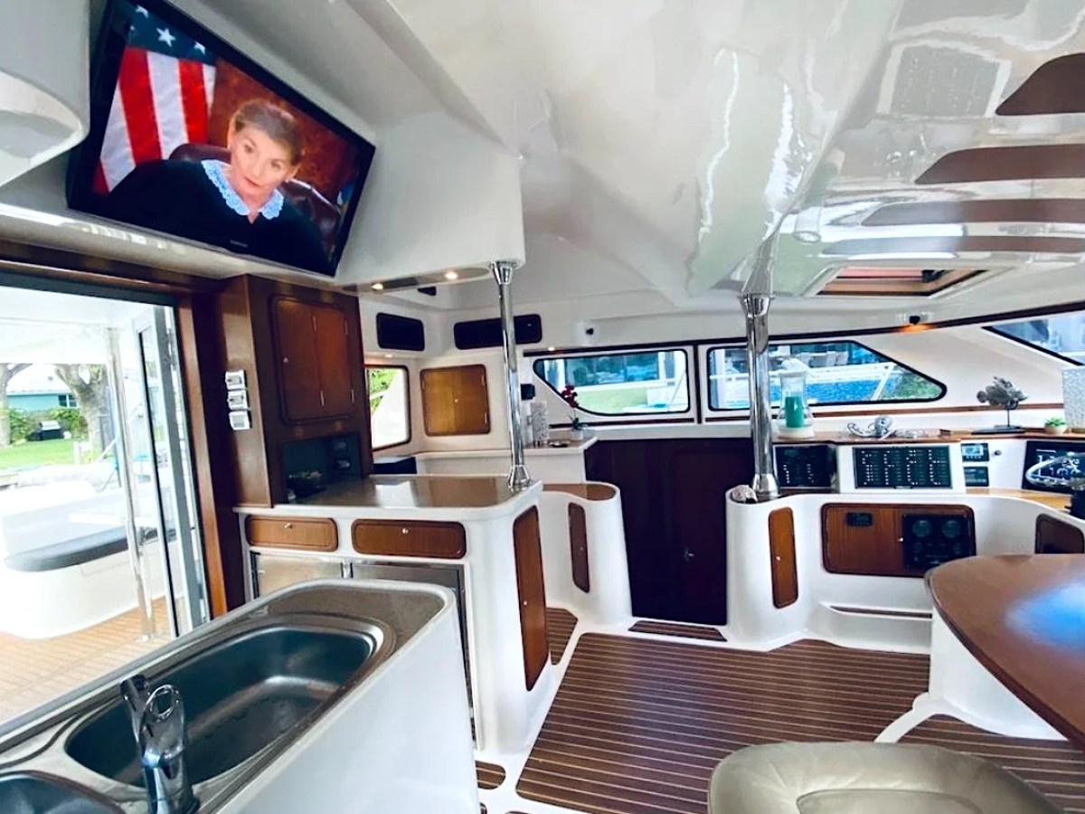 This 50 foot AfriCat Yacht Charter features a spacious luxury salon with dining area, entertainment television, galley sink, panoramic windows, and open-air access while cruising near Fort Myers and Sanibel Island.