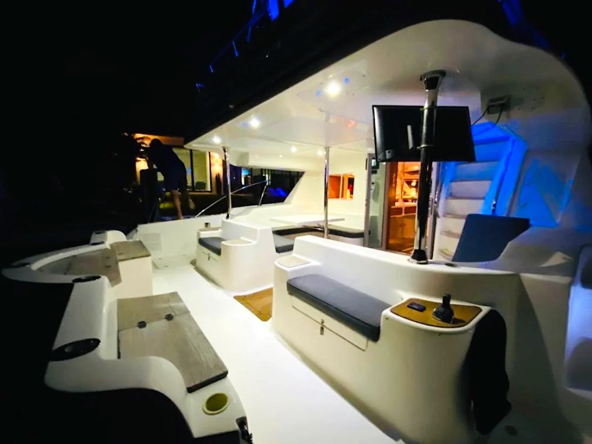 This 50 foot AfriCat Yacht Charter showcases an illuminated aft deck lounge at night with wraparound seating, open-air gathering space, and ambient lighting while docked in Fort Myers along Southwest Florida waterways.