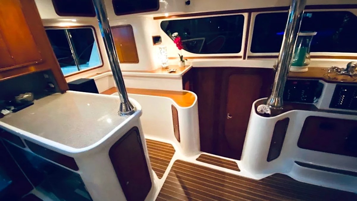 This 50 foot AfriCat Yacht Charter features an elegant illuminated galley and salon passageway with premium countertops, rich wood finishes, and ambient evening lighting while cruising near Fort Myers and Sanibel Island.