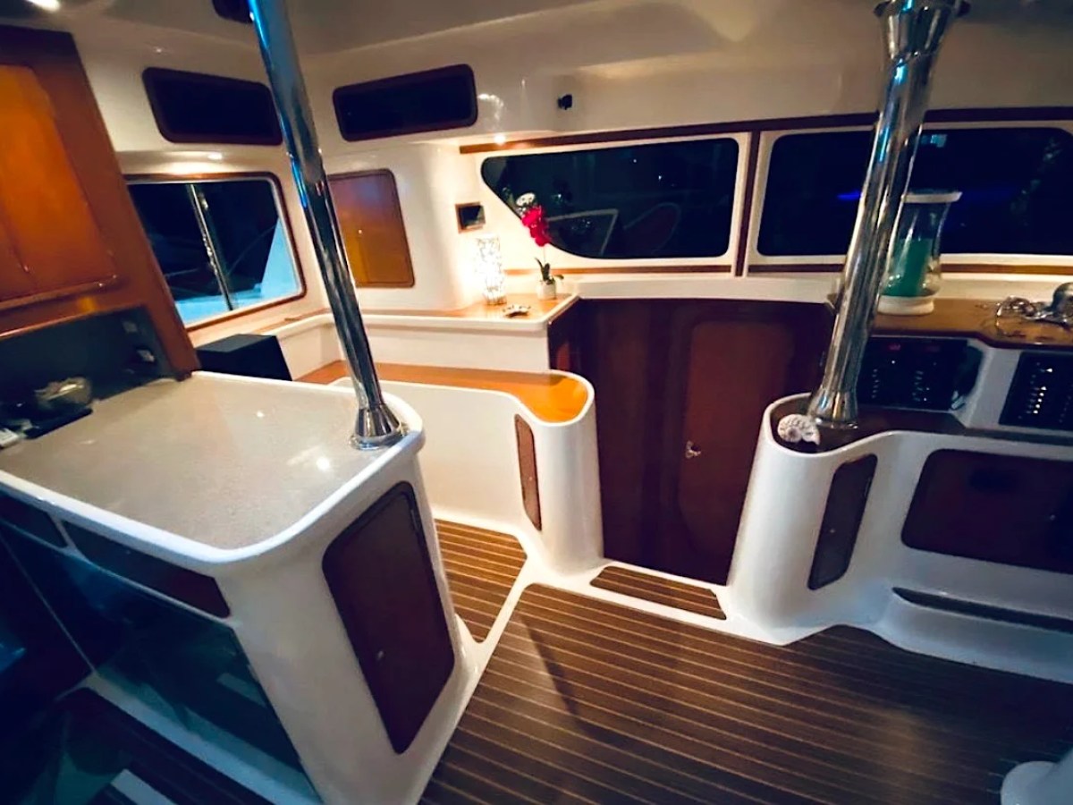 This 50 foot AfriCat Yacht Charter features an elegant illuminated galley and salon passageway with premium countertops, rich wood finishes, and ambient evening lighting while cruising near Fort Myers and Sanibel Island.