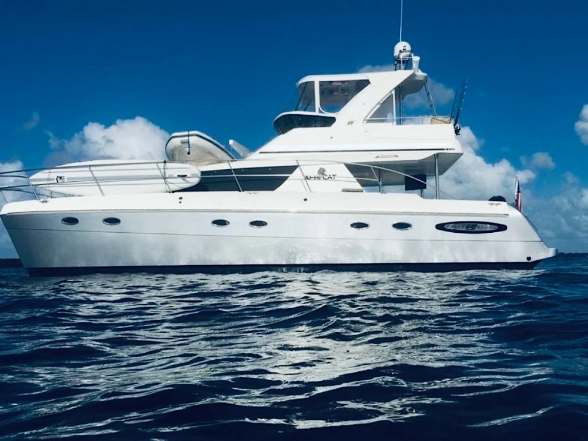 This 50 foot AfriCat Yacht Charter cruises through Fort Myers waterways with a sleek power catamaran profile, expansive flybridge, and calm Gulf Coast waters visible beneath a bright Southwest Florida sky.