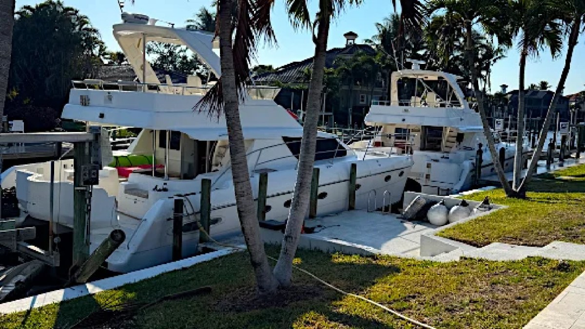 This 50 foot AfriCat Yacht Charter is docked along a waterfront canal in Fort Myers, showcasing the spacious catamaran design, flybridge, and private yacht lifestyle surrounded by Southwest Florida palm-lined waterways.