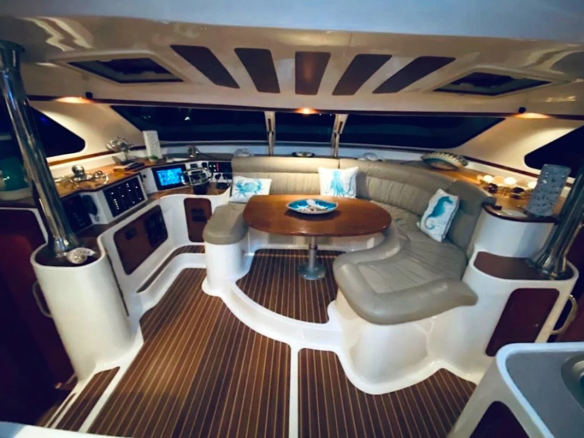 This 50 foot AfriCat Yacht Charter features a wraparound salon dining lounge with curved seating, wood table accents, and panoramic windows while docked in Fort Myers near Southwest Florida waterways.