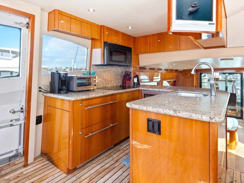 Gourmet galley and open-concept salon aboard a 64' Hatteras Yacht Charter featuring granite countertops, premium appliances, custom cabinetry, and seamless indoor-outdoor entertaining space.