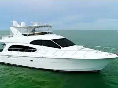 64' Hatteras Yacht Charter cruising the waters of Marco Island with a sleek white profile, elevated flybridge, and expansive foredeck visible against the Gulf of America horizon.