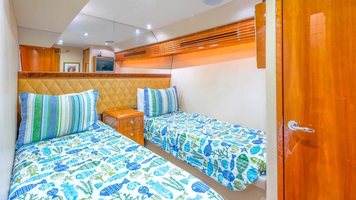 Twin guest stateroom aboard a 64' Hatteras Yacht Charter featuring two comfortable single berths, custom wood finishes, nautical-themed bedding, and private guest accommodations.