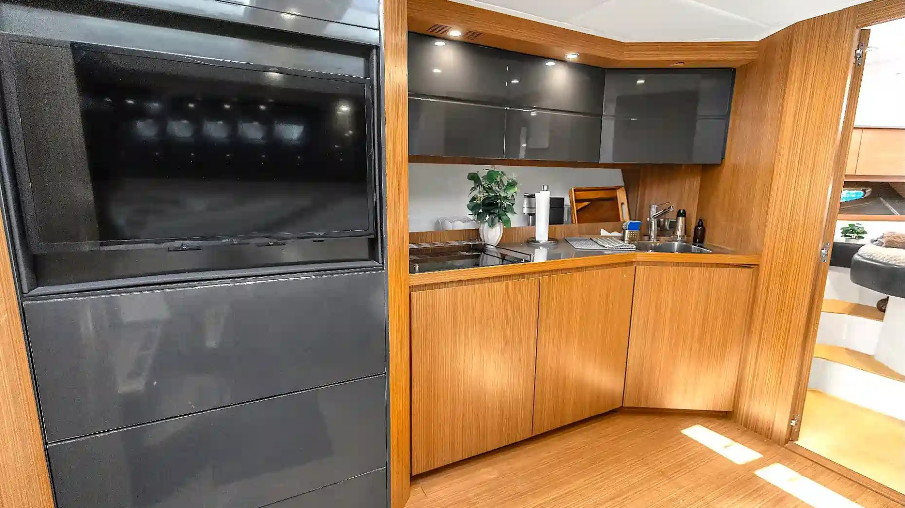 Modern galley aboard a 50' Azimut Yacht Charter featuring wood cabinetry, integrated sink, countertop workspace, and entertainment area with contemporary finishes in Miami.