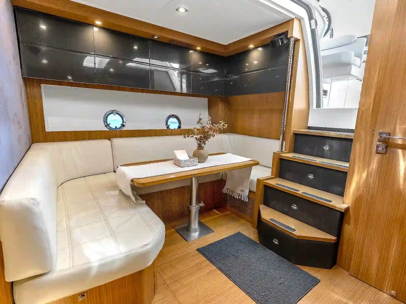 Elegant interior salon aboard a 50' Azimut Yacht Charter featuring wraparound leather seating, dining table, premium wood finishes, and modern luxury yacht design.