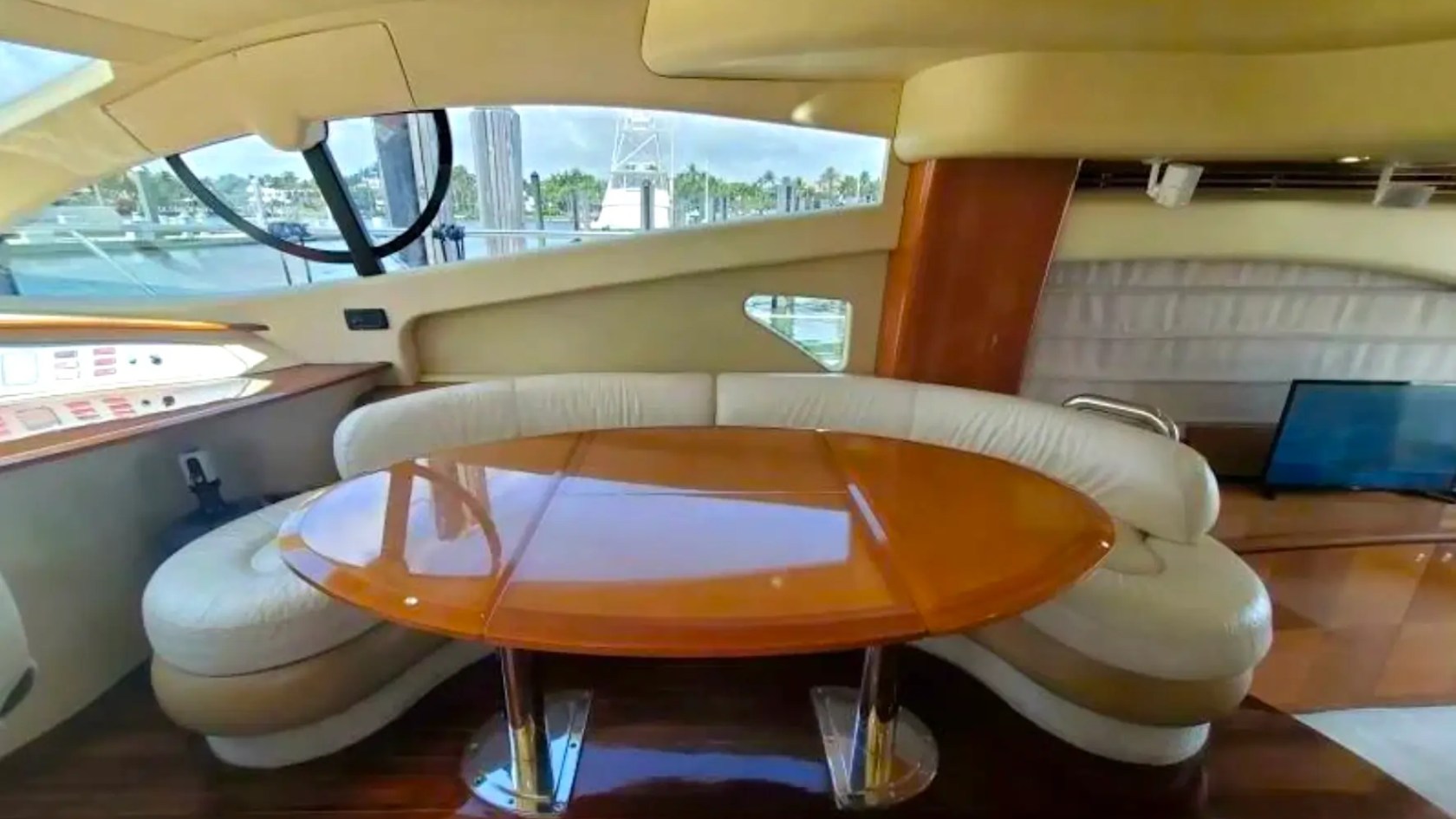57' Azimut Yacht Charter dinette featuring a curved leather dining lounge, high-gloss wood table, panoramic windows, and elegant onboard dining space in Miami.