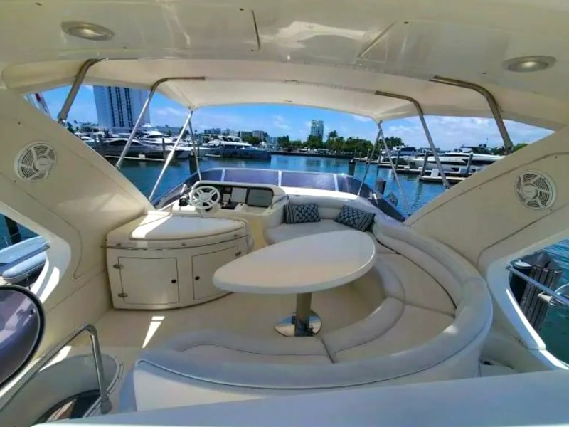 57' Azimut Yacht Charter flybridge featuring a spacious lounge, helm station, and wraparound seating overlooking Miami's luxury marina.