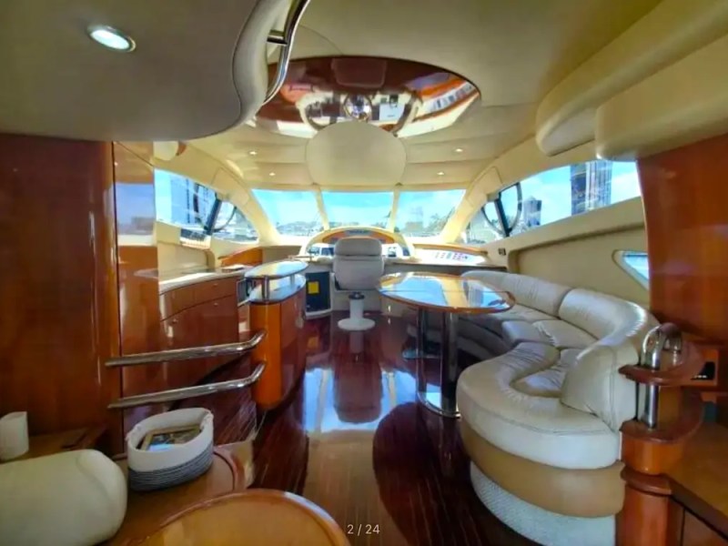 57' Azimut Yacht Charter helm salon featuring panoramic windshield views, polished wood cabinetry, curved lounge seating, and an open navigation station cruising through Miami.