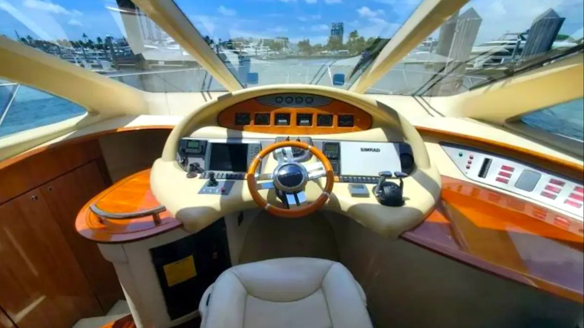 57' Azimut Yacht Charter helm station showcasing premium navigation controls, Simrad electronics, panoramic windshield views, and the captain's command center in Miami.