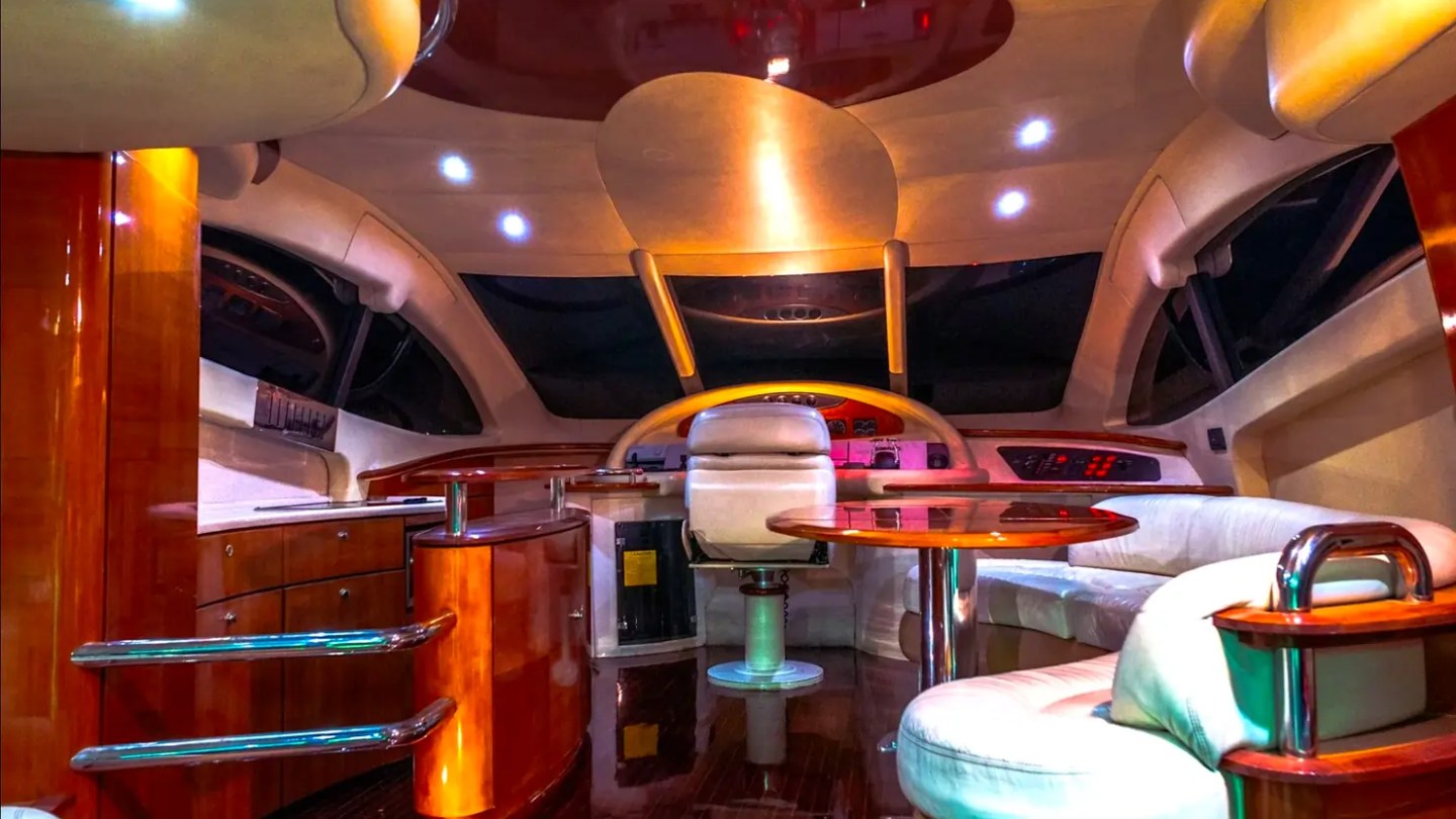57' Azimut Yacht Charter salon at night featuring ambient LED lighting, premium helm station, and elegant lounge seating in Miami.
