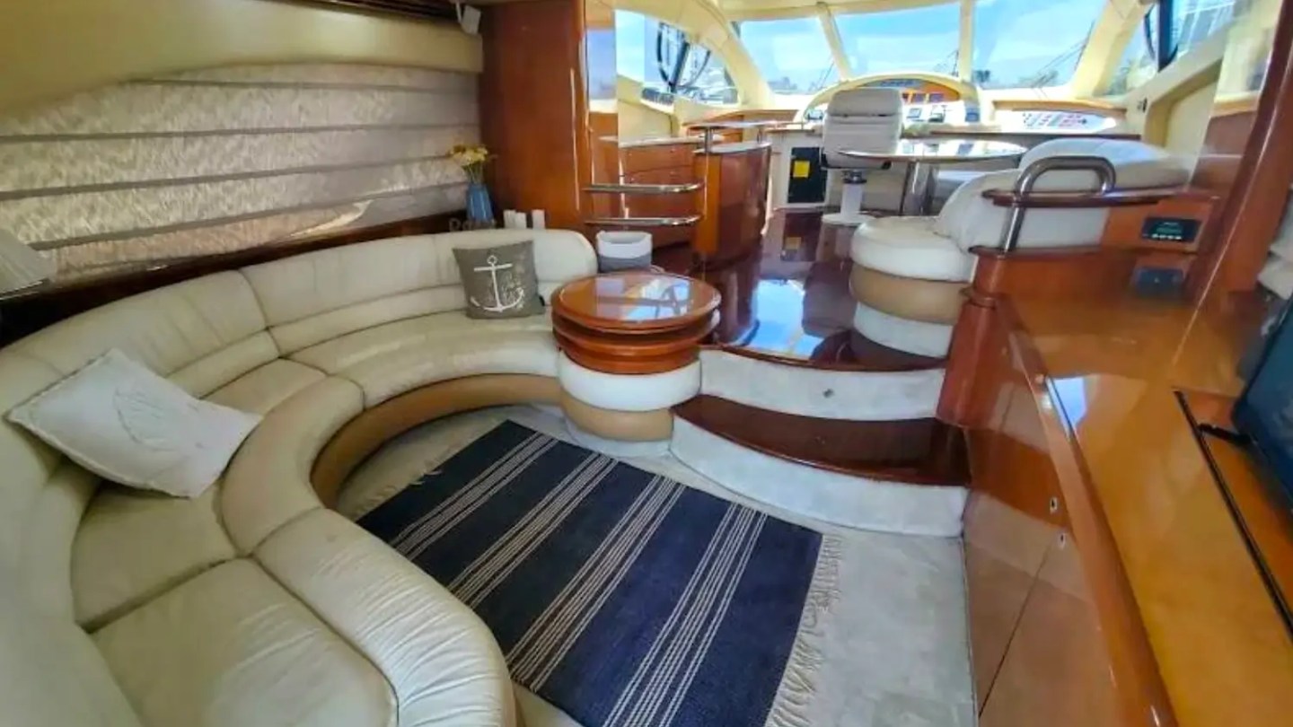 57' Azimut Yacht Charter salon featuring curved leather seating, glossy wood finishes, panoramic helm access, and an inviting lounge for entertaining in Miami.