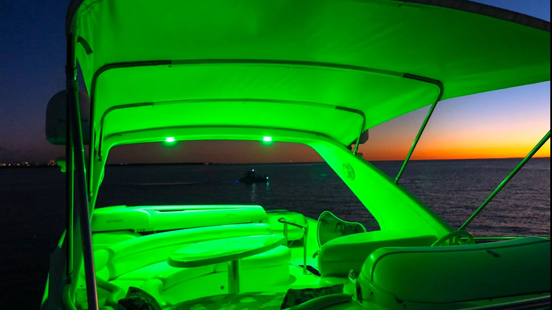 57' Azimut Yacht Charter flybridge at sunset illuminated with ambient LED lighting overlooking the Miami coastline and Atlantic Ocean.