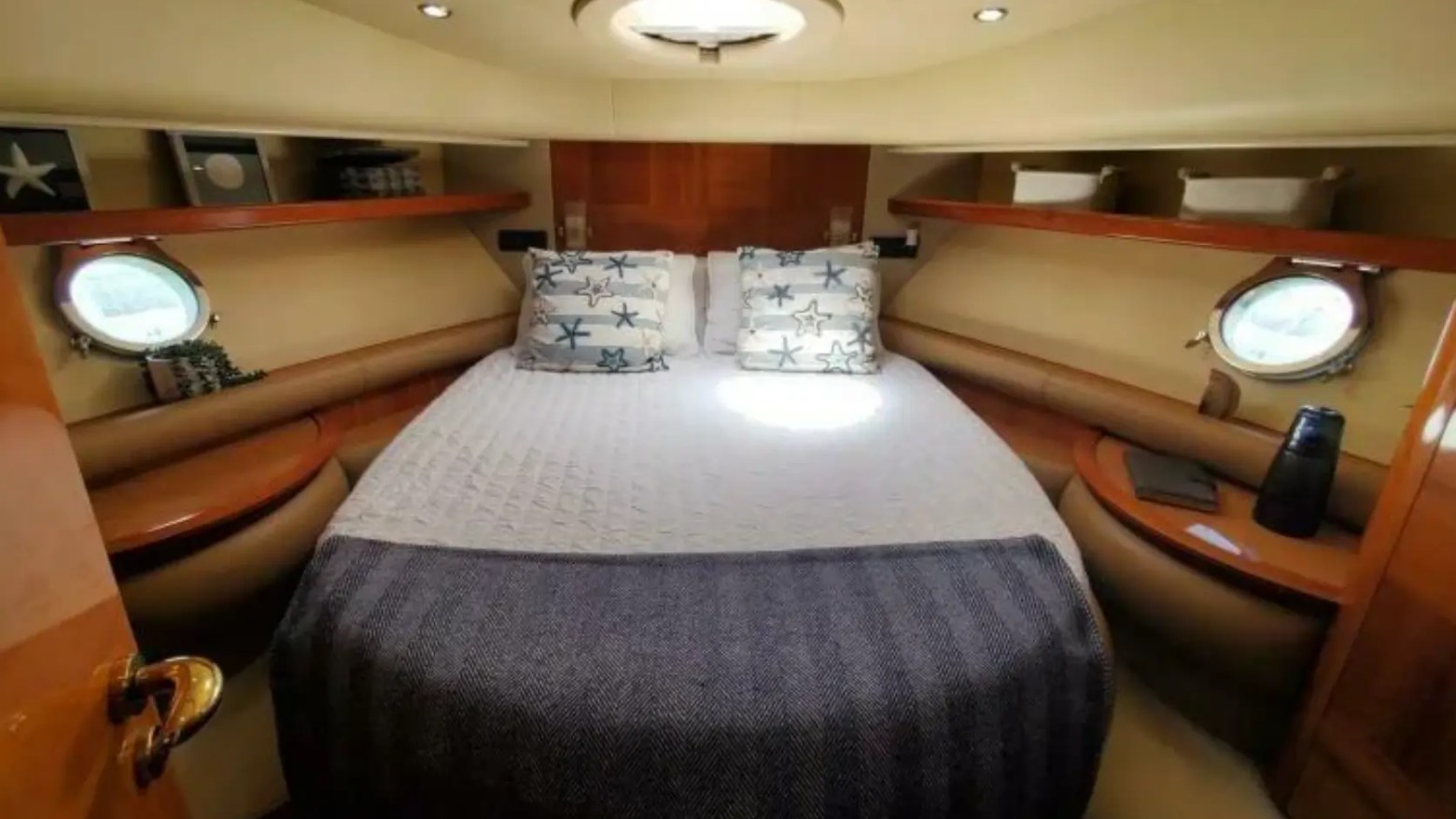 57' Azimut Yacht Charter VIP stateroom featuring a full-size berth, warm wood cabinetry, porthole windows, and elegant overnight accommodations in Miami.