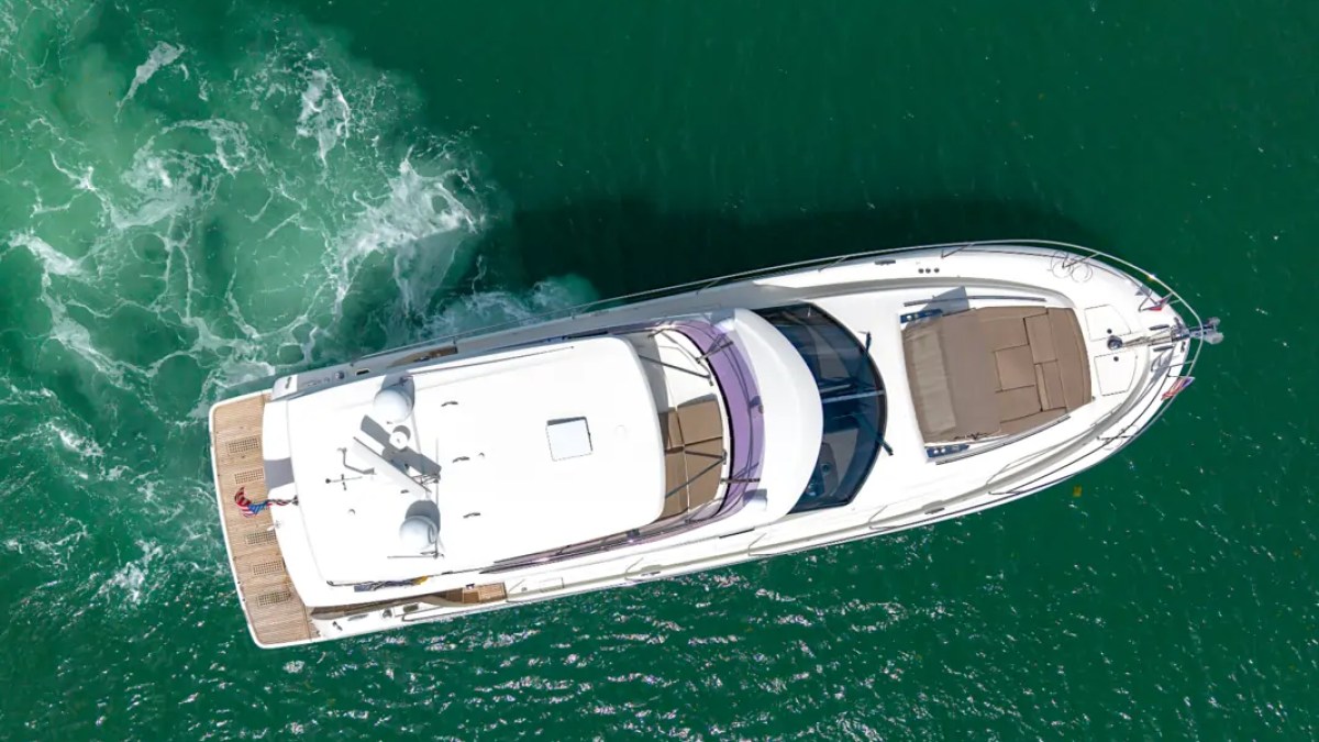 58' Prestige Yacht Charter aerial view showcasing the spacious flybridge, bow sun pad, and swim platform cruising the turquoise waters of Biscayne Bay in Miami.