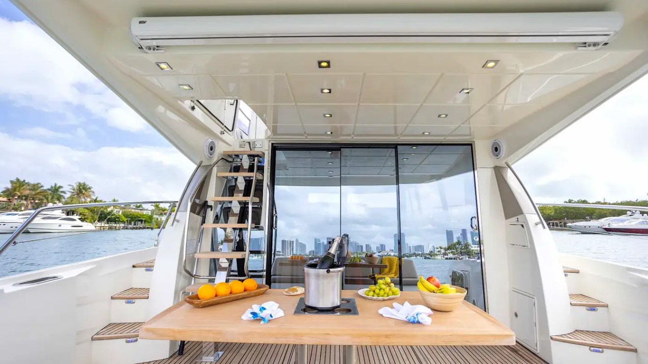 58' Prestige Yacht Charter spacious aft cockpit with alfresco dining table, champagne service, and panoramic Miami waterfront views along Biscayne Bay.