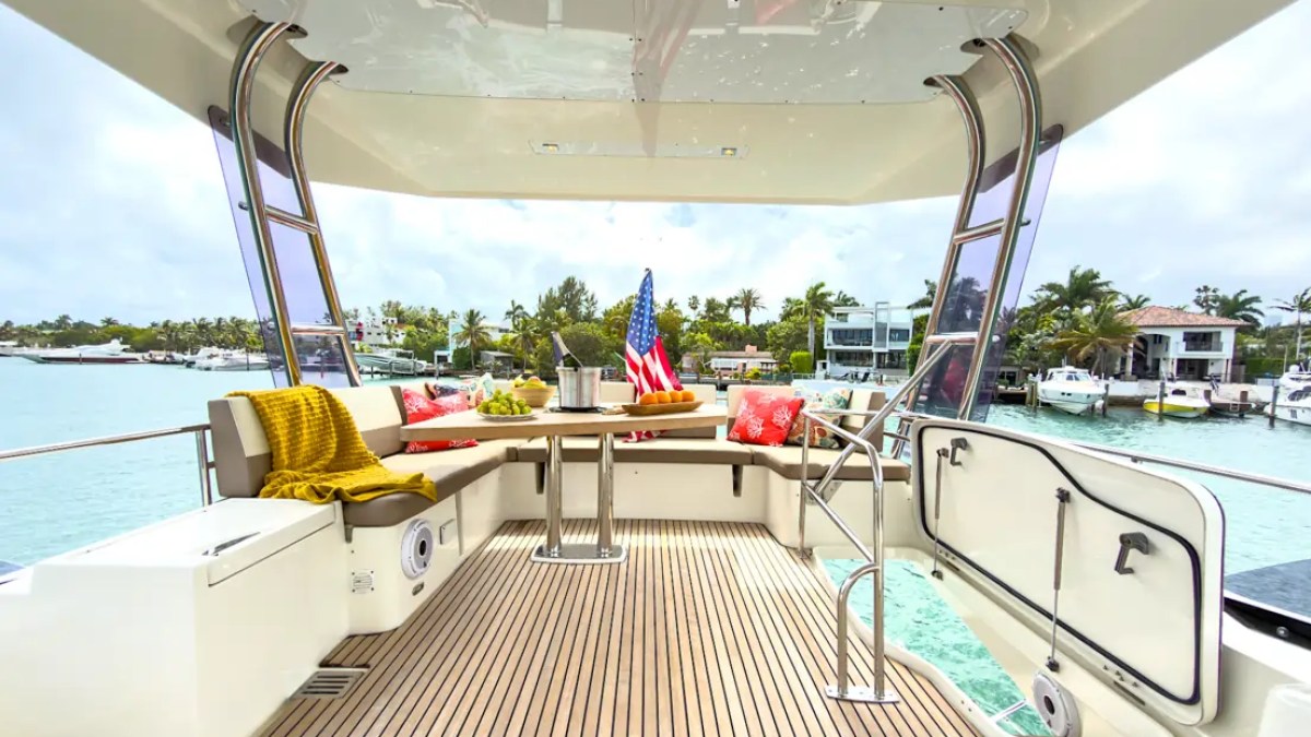 58' Prestige Yacht Charter aft cockpit featuring teak decking, alfresco dining, and an open transom overlooking Biscayne Bay near Miami Beach waterfront estates.