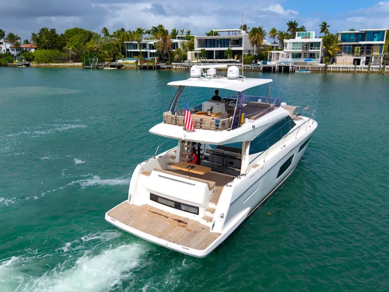 58' Prestige Yacht Charter cruising Biscayne Bay with a spacious aft deck, flybridge lounge, and oversized swim platform near Miami Beach luxury waterfront homes.