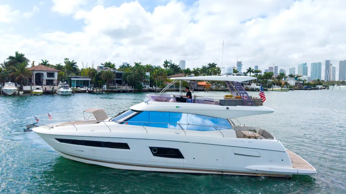 58' Prestige Yacht Charter cruising Biscayne Bay with the Miami skyline and waterfront estates showcasing sleek flybridge styling and luxury performance.