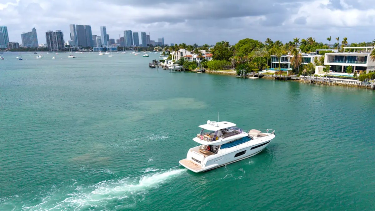 58' Prestige Yacht Charter cruising across Biscayne Bay with the Miami skyline and Star Island waterfront estates creating a spectacular South Florida aerial backdrop.