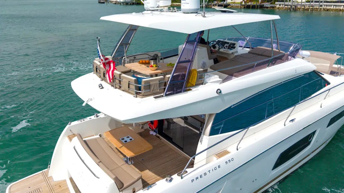 58' Prestige Yacht Charter showcasing its spacious flybridge, aft cockpit, and panoramic cruising design while navigating Biscayne Bay near Miami Beach luxury waterfront estates.