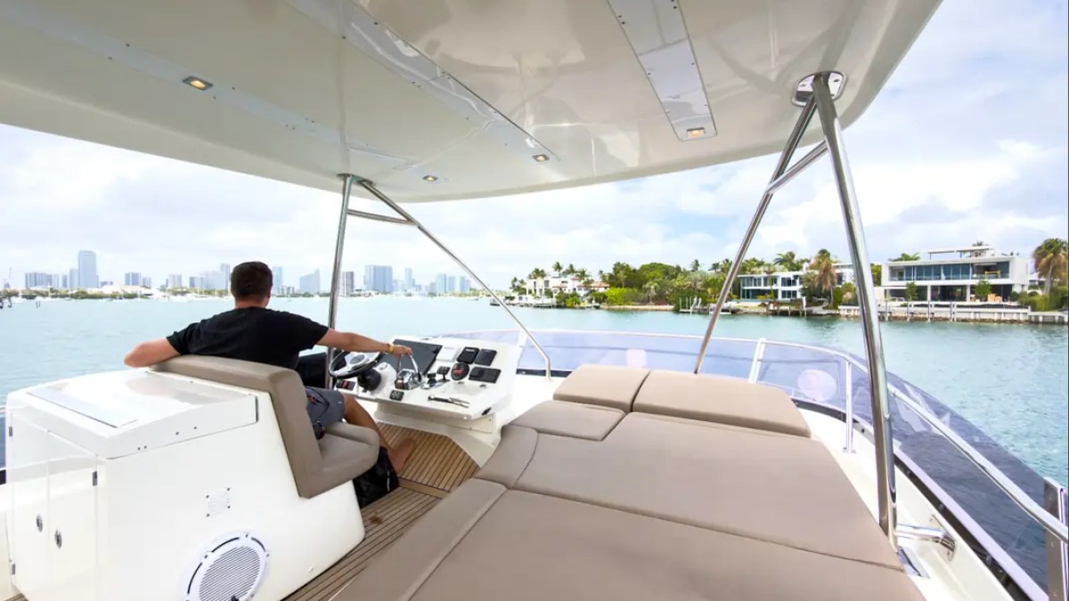 58' Prestige Yacht Charter flybridge helm with oversized sun lounge and panoramic Biscayne Bay views while cruising near the Miami Beach waterfront.