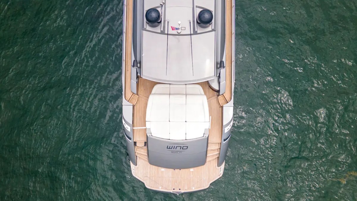 64' Pershing Yacht Charter aerial view showcasing the expansive teak swim platform, aft sun pad, and luxury cockpit layout cruising the waters of Miami.
