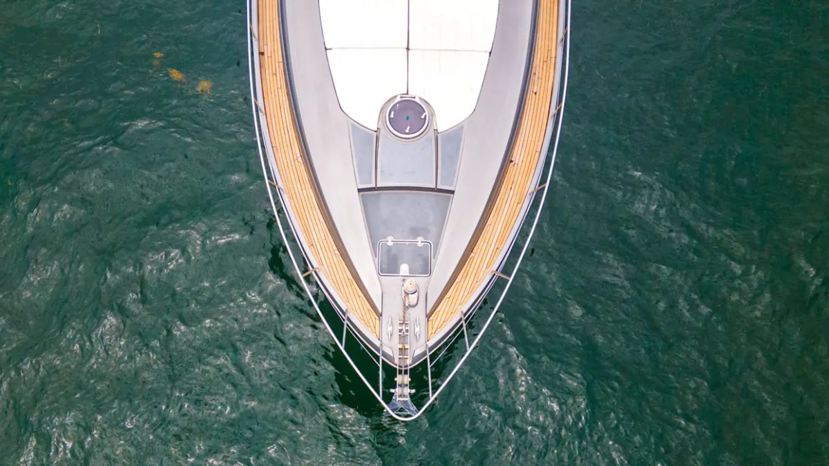 64' Pershing Yacht Charter aerial view highlighting the expansive foredeck sun pad and teak walkways while anchored in the emerald waters of Biscayne Bay, Miami.