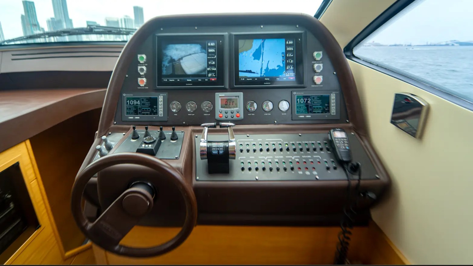 64' Pershing Yacht Charter advanced helm station featuring dual Garmin navigation displays, electronic controls, and premium captain's console while cruising Miami waters.