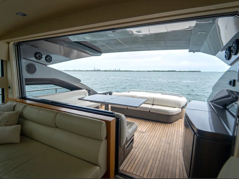 64' Pershing Yacht Charter open salon seamlessly connecting to the aft cockpit lounge with panoramic ocean views while cruising off Miami Beach.