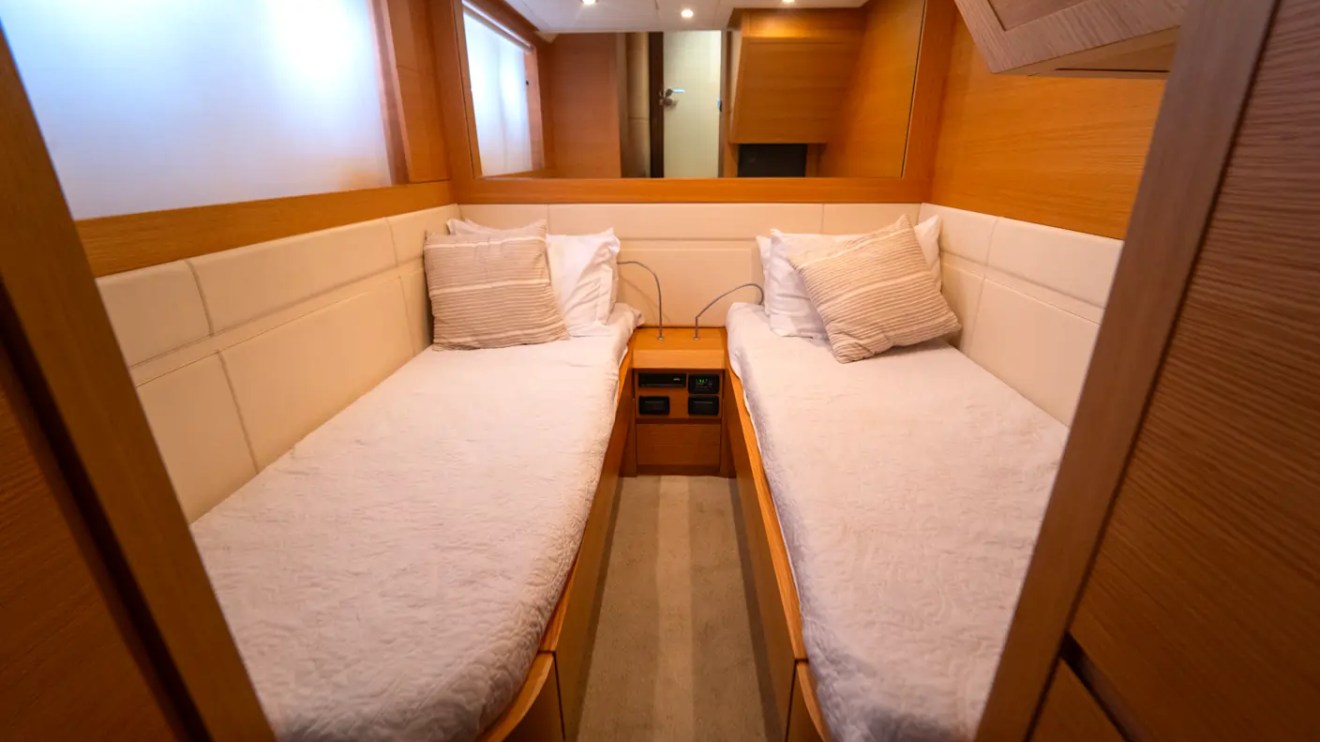 64' Pershing Yacht Charter guest cabin with twin beds, premium finishes, and elegant accommodations for overnight cruises in Miami aboard a luxury yacht.