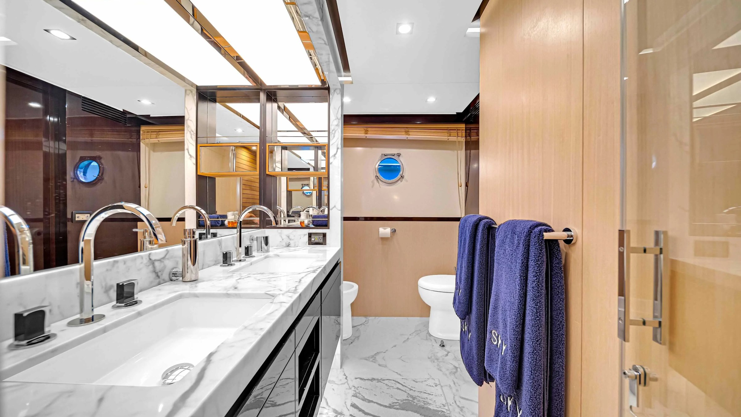 84' Azimut Yacht Charter ensuite bathroom featuring dual marble vanities, polished fixtures, glass shower enclosure, and contemporary luxury finishes aboard this Miami yacht.