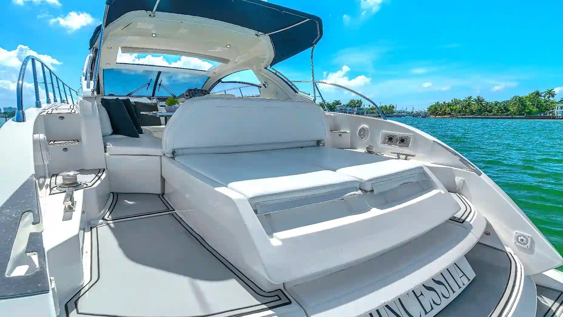 Spacious aft cockpit lounge aboard a 50' Azimut Yacht Charter in Miami featuring a large sun pad, shaded seating area, and panoramic waterfront views.