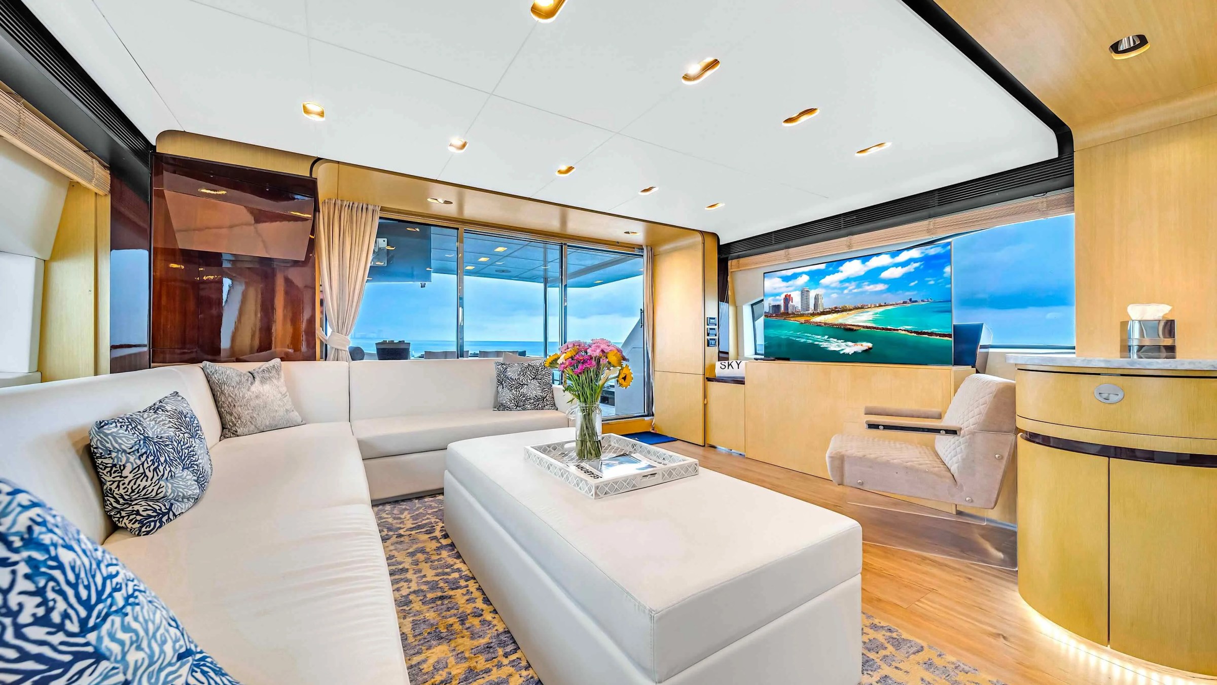 84' Azimut Yacht Charter luxury salon featuring contemporary lounge seating, entertainment center, panoramic windows, and elegant finishes while cruising near Miami Beach.