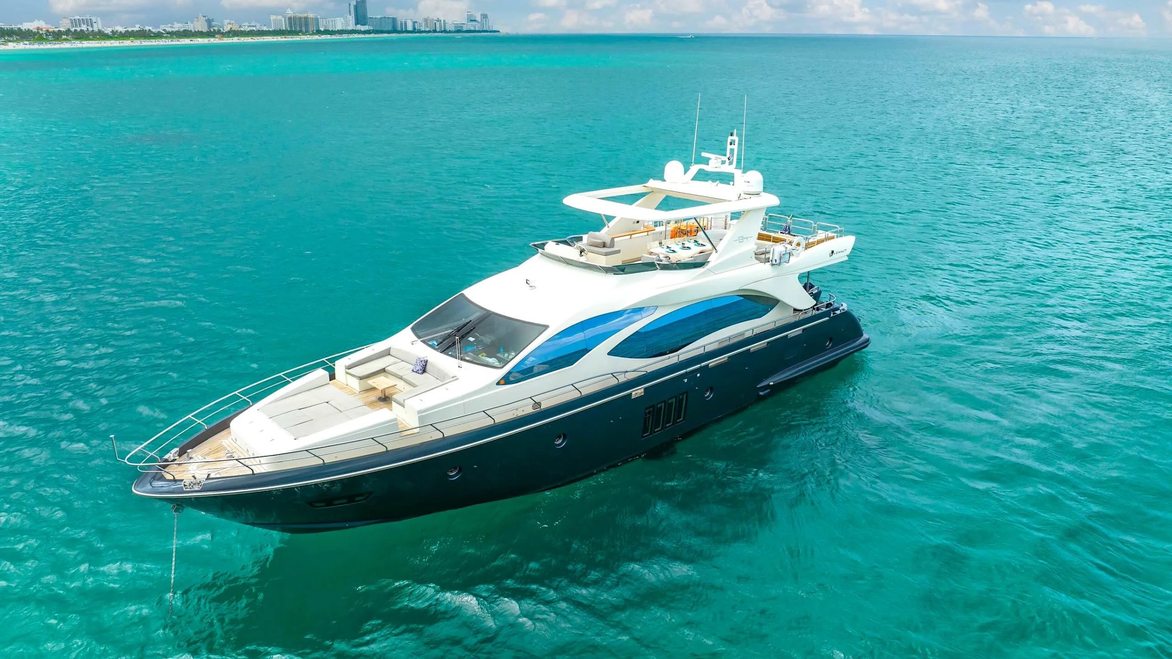 84' Azimut Yacht Charter captured from an offshore aerial near Miami Beach, showcasing sleek Italian styling, expansive bow lounge, and turquoise Atlantic waters.