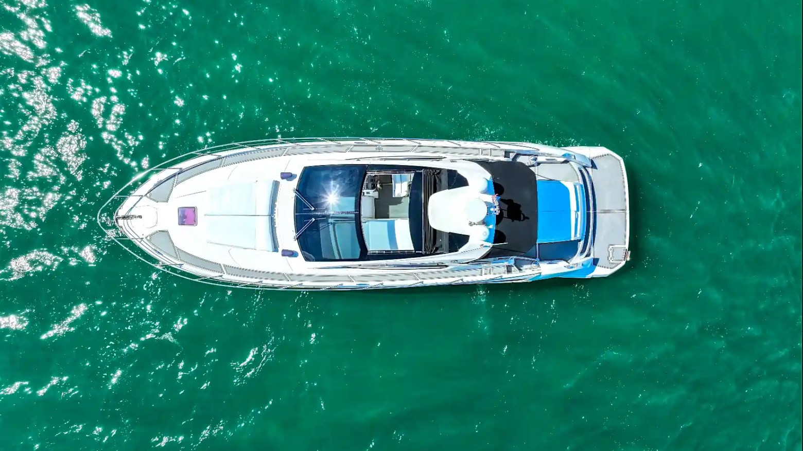 Aerial top-down view of a 50' Azimut Yacht Charter floating in the crystal-clear turquoise waters of Biscayne Bay, showcasing the yacht's sleek layout and luxury design.