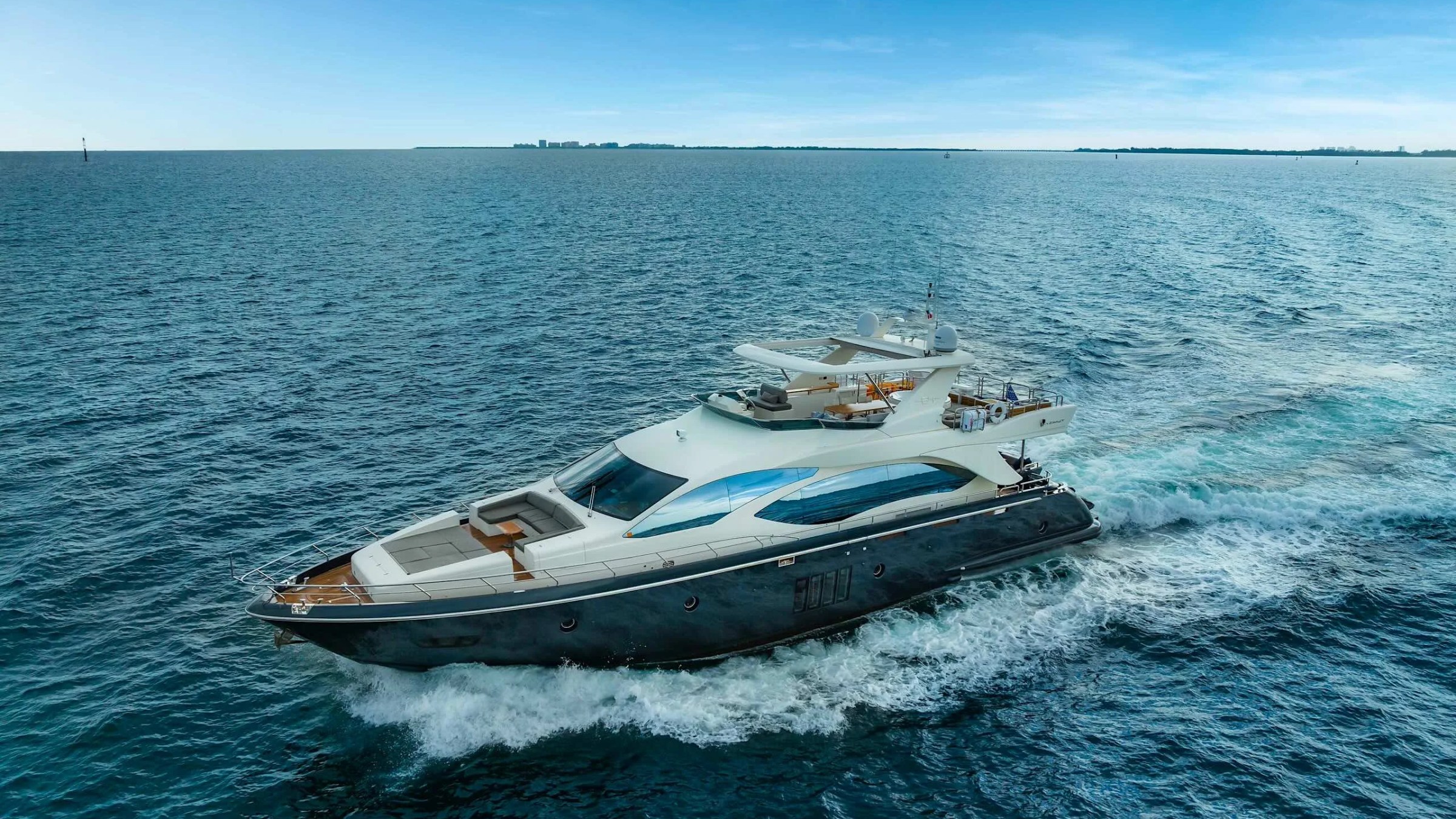 84' Azimut Yacht Charter underway across Biscayne Bay with a drone shot capturing the sleek profile, flybridge deck, and open-water cruising near Miami.