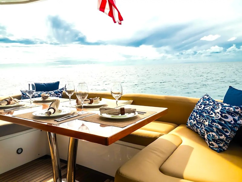 75' Sunseeker Yacht Charter aft deck dining area featuring wraparound seating, table settings, oceanfront views, and open-air entertaining space near Nassau.