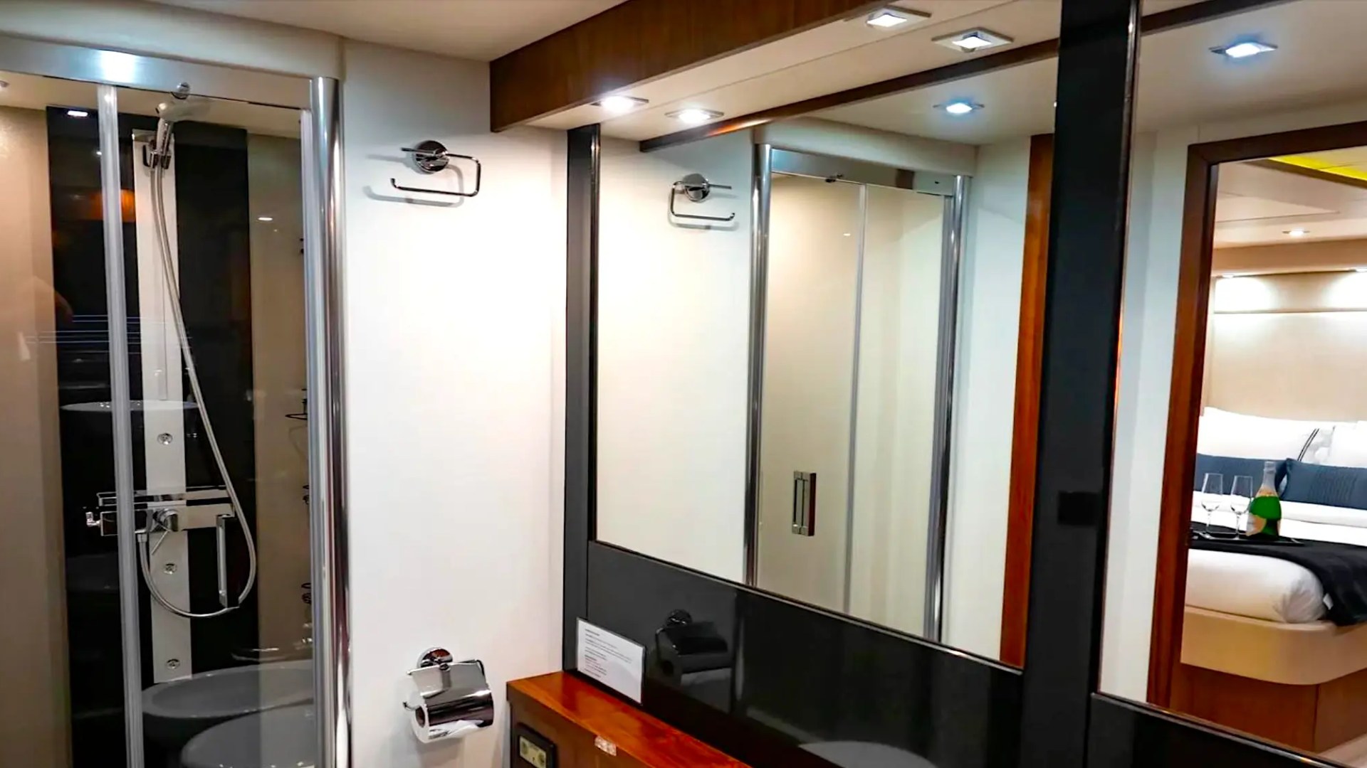 75' Sunseeker Yacht Charter ensuite bathroom featuring a glass-enclosed shower, illuminated vanity mirror, modern fixtures, and direct access to the yacht's luxury stateroom near Nassau.