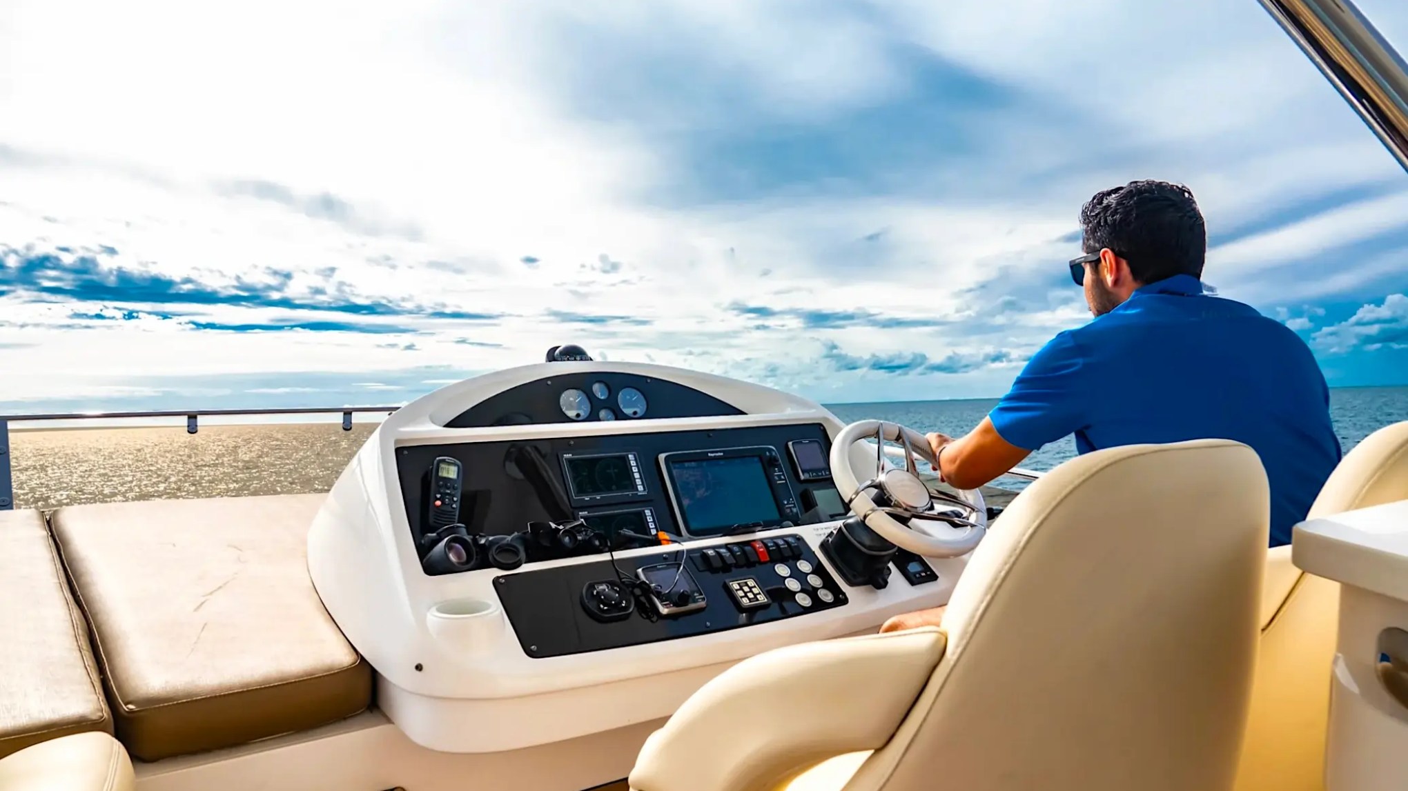 75' Sunseeker Yacht Charter flybridge helm station featuring navigation displays, captain's chair, open-air controls, and sweeping ocean views near Nassau in The Bahamas.