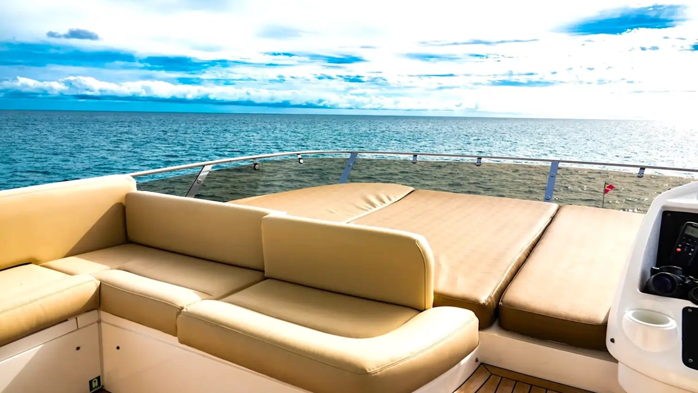 75' Sunseeker Yacht Charter flybridge lounge featuring wraparound seating, oversized sun pad, teak decking, and panoramic ocean views near Nassau in The Bahamas.