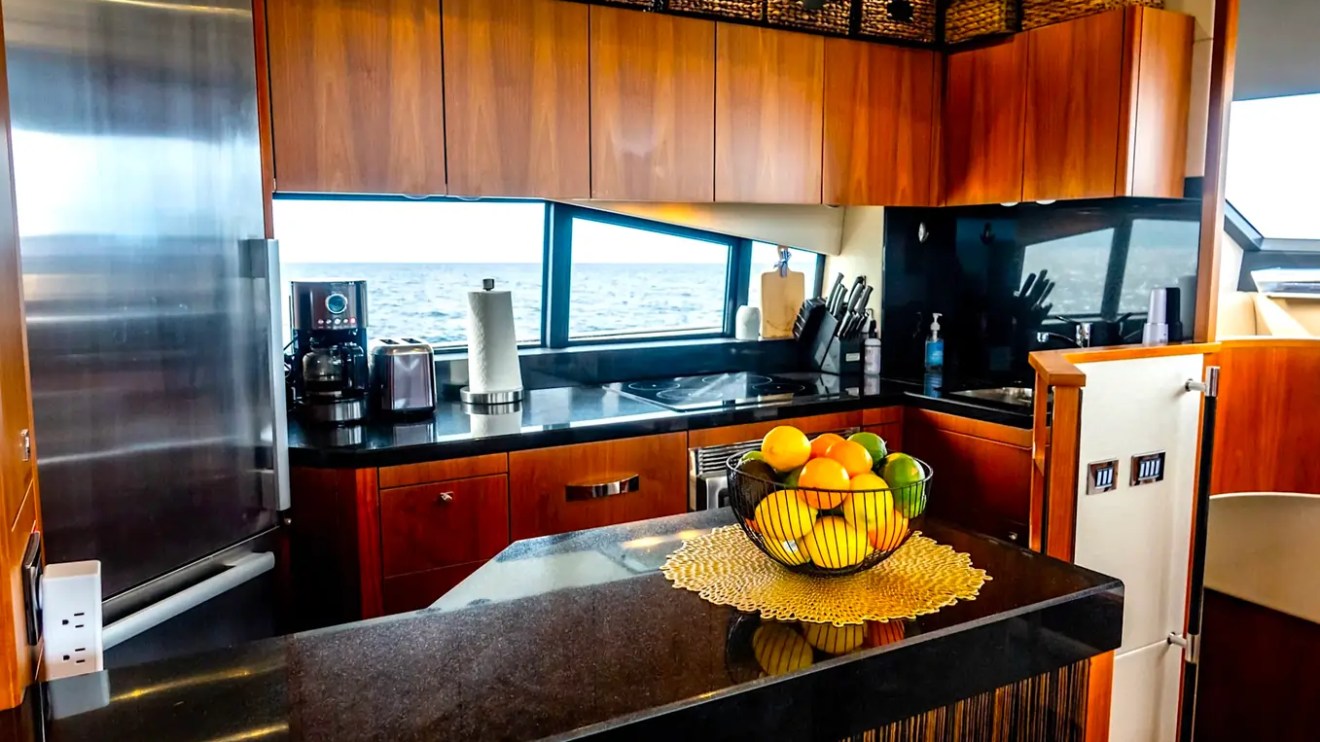 75' Sunseeker Yacht Charter galley featuring stone countertops, wood cabinetry, stainless appliances, panoramic windows, and an open-concept layout in Nassau.