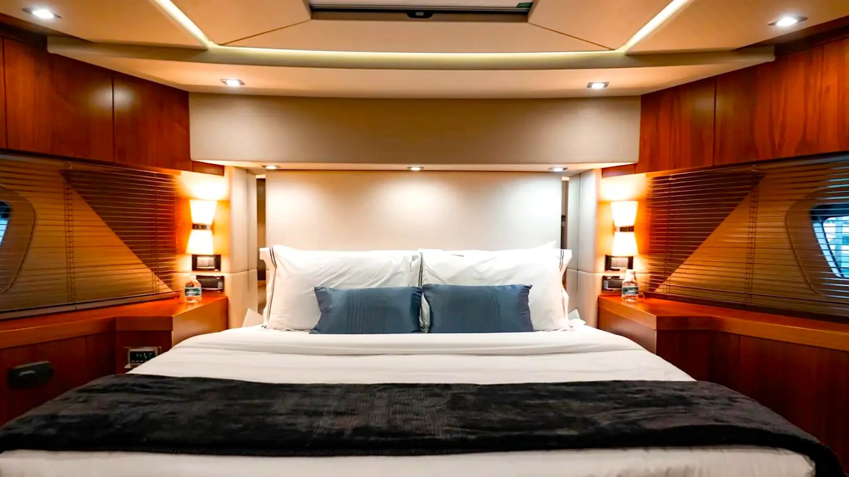 75' Sunseeker Yacht Charter master stateroom featuring a king-size berth, wood cabinetry, ambient lighting, and hull-side windows in Nassau, The Bahamas.