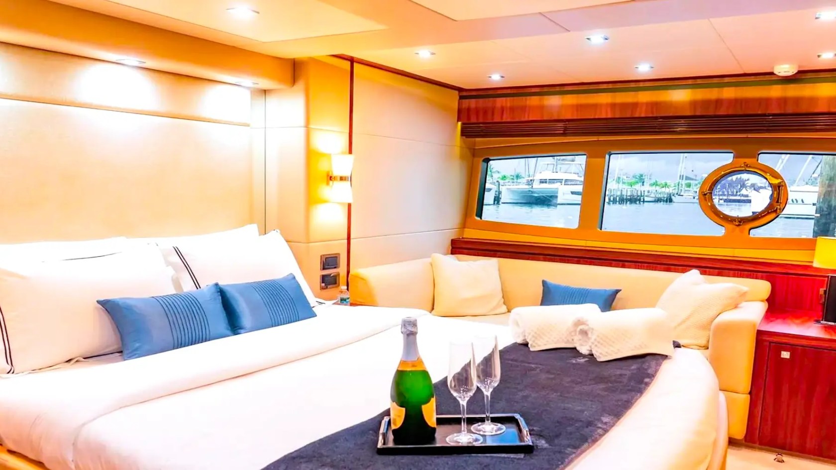75' Sunseeker Yacht Charter master suite featuring a king-size berth, lounge seating, panoramic windows, and elegant wood finishes docked near Nassau.