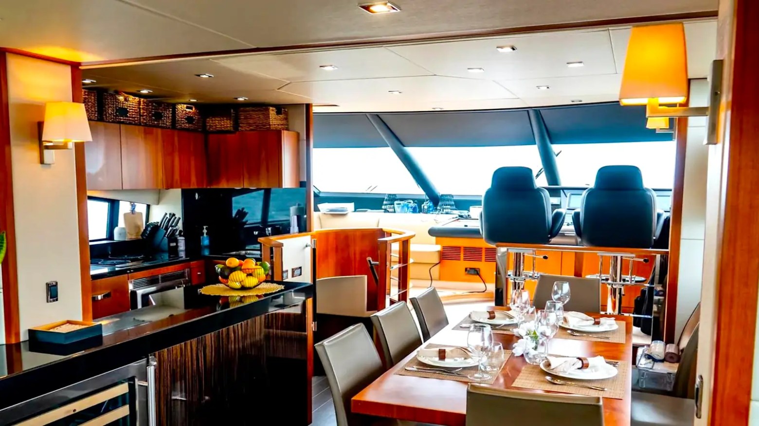 75' Sunseeker Yacht Charter interior featuring an open-concept galley, formal dining area, elevated helm station, and panoramic windows overlooking Nassau waters.