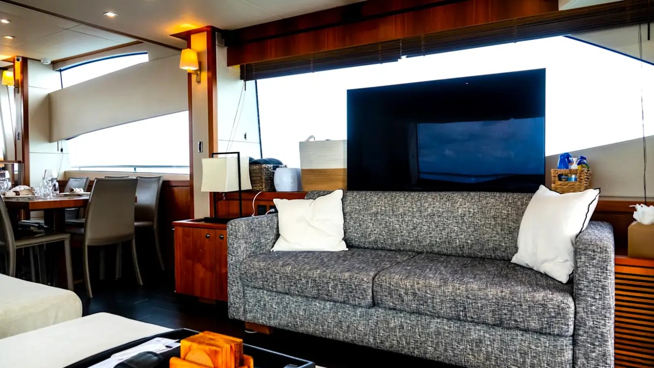 75' Sunseeker Yacht Charter salon featuring a contemporary lounge sofa, entertainment center, dining area, panoramic windows, and refined wood finishes in Nassau.