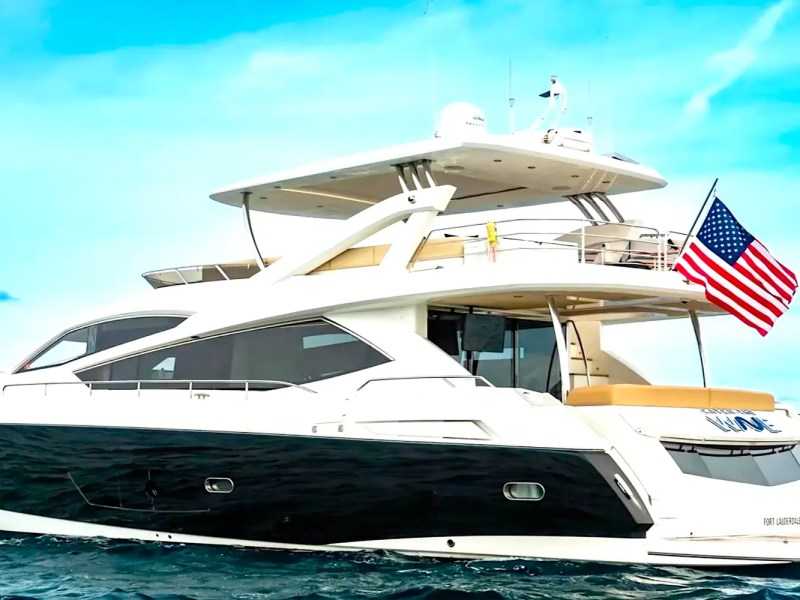 75' Sunseeker Yacht Charter cruising offshore near Nassau with a sleek black hull, elevated flybridge, open aft deck seating, and Bahamas blue water views.