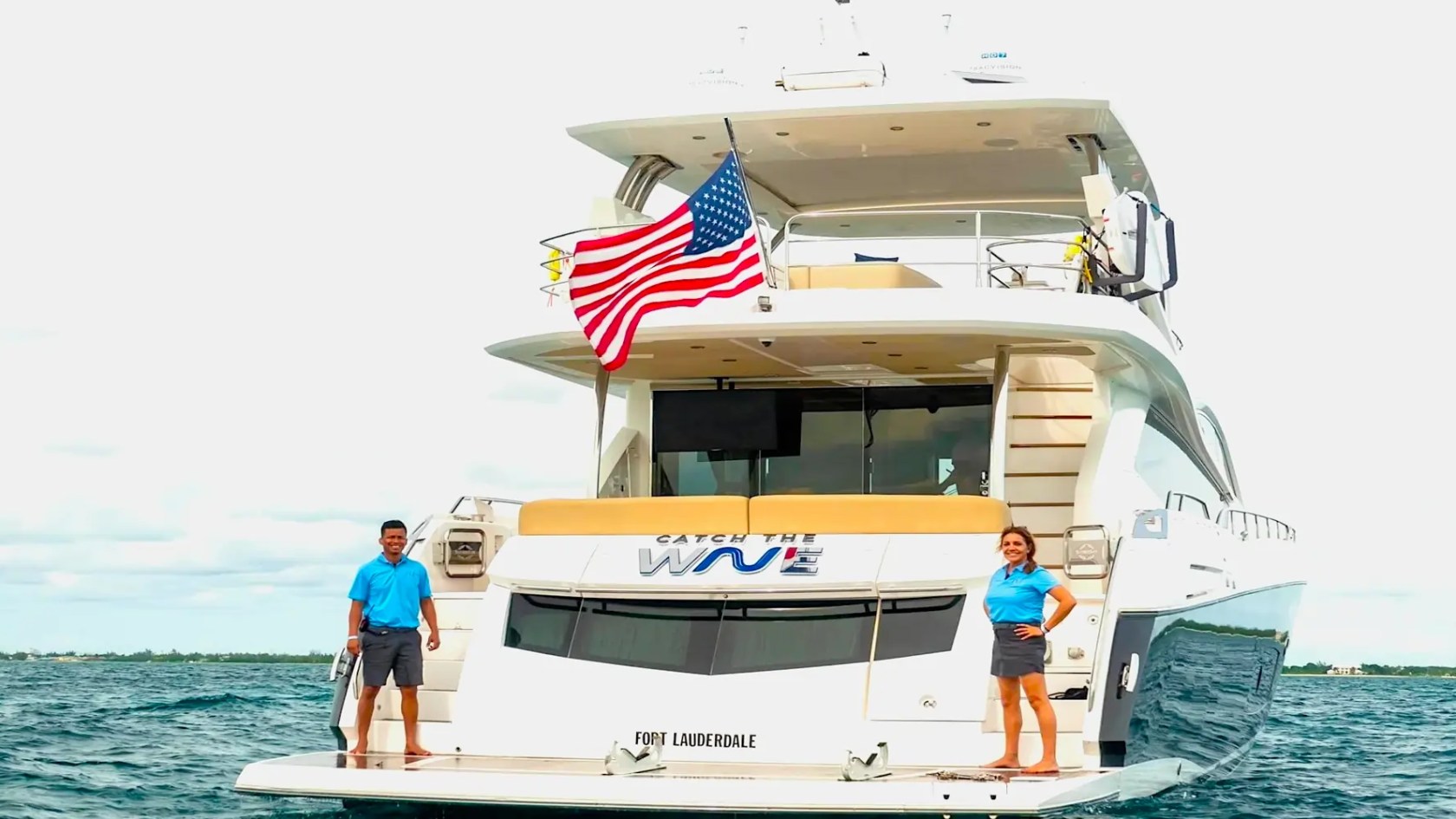 75' Sunseeker Yacht Charter viewed from the stern in Nassau, showcasing the spacious swim platform, aft deck access, flybridge levels, and calm Bahamas waters.